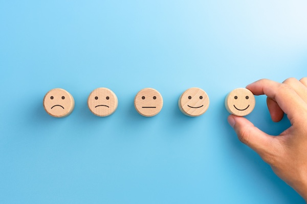 Customer service evaluation and satisfaction survey concepts. The client's hand picked the happy face smile face icon on wooden cube on blue background. copy space Customer service evaluation and satisfaction survey concepts. The client's hand picked the happy face smile face icon on wooden cube on blue background. copy space